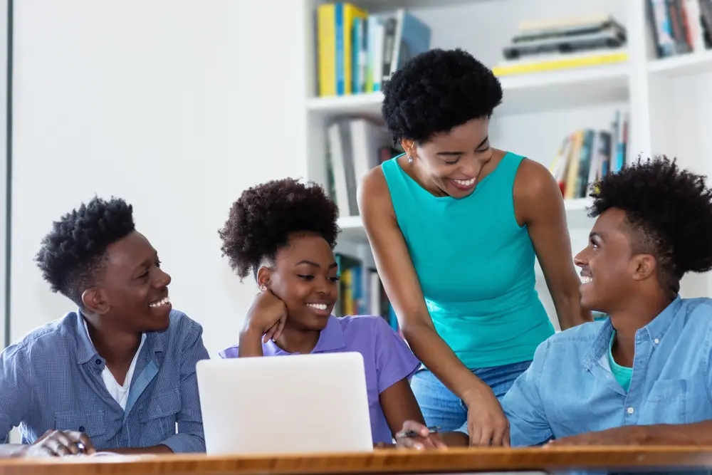 a picture of teens smiling together in front of laptop
